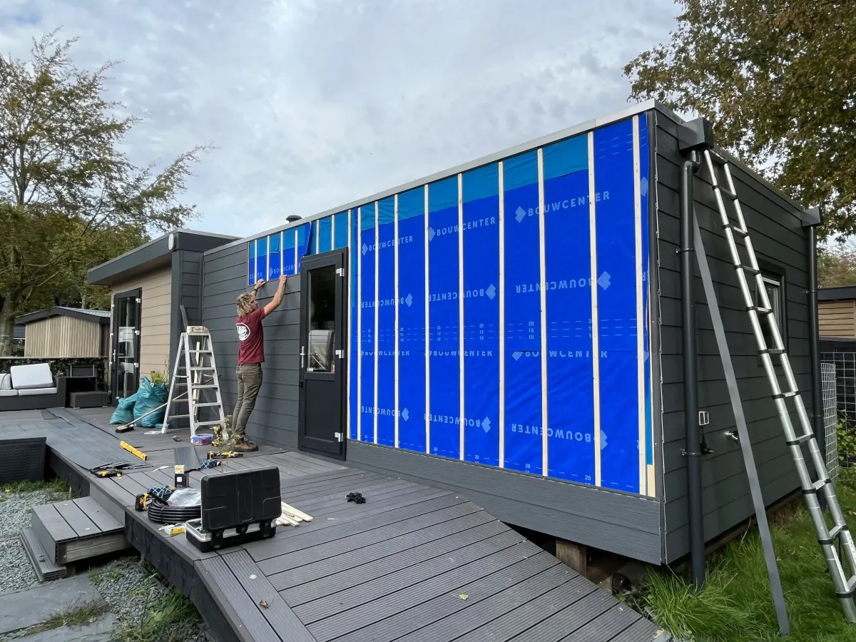 Nieuwe grijze buitenbekleding wordt op een chalet gemonteerd