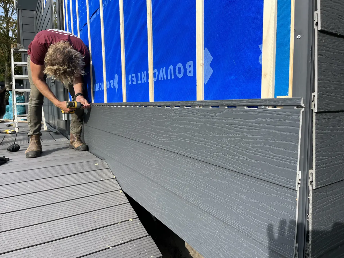 Duncan aan het werk aan de gevel van een chalet