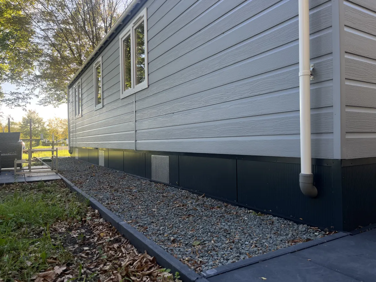 Chalet met nieuwe donkere onderafzetting en grindstrook